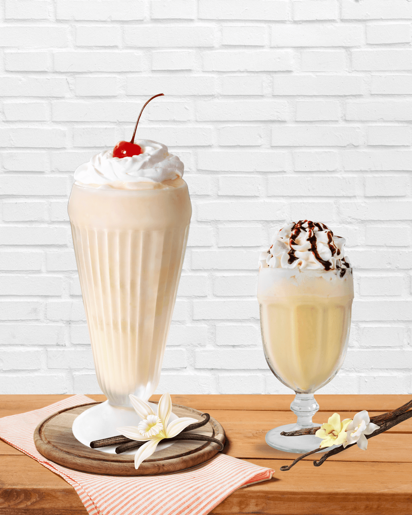 Two vanilla lattes topped with whipped cream and cherry and chocolate drizzle made using the best vanilla powder for lattes