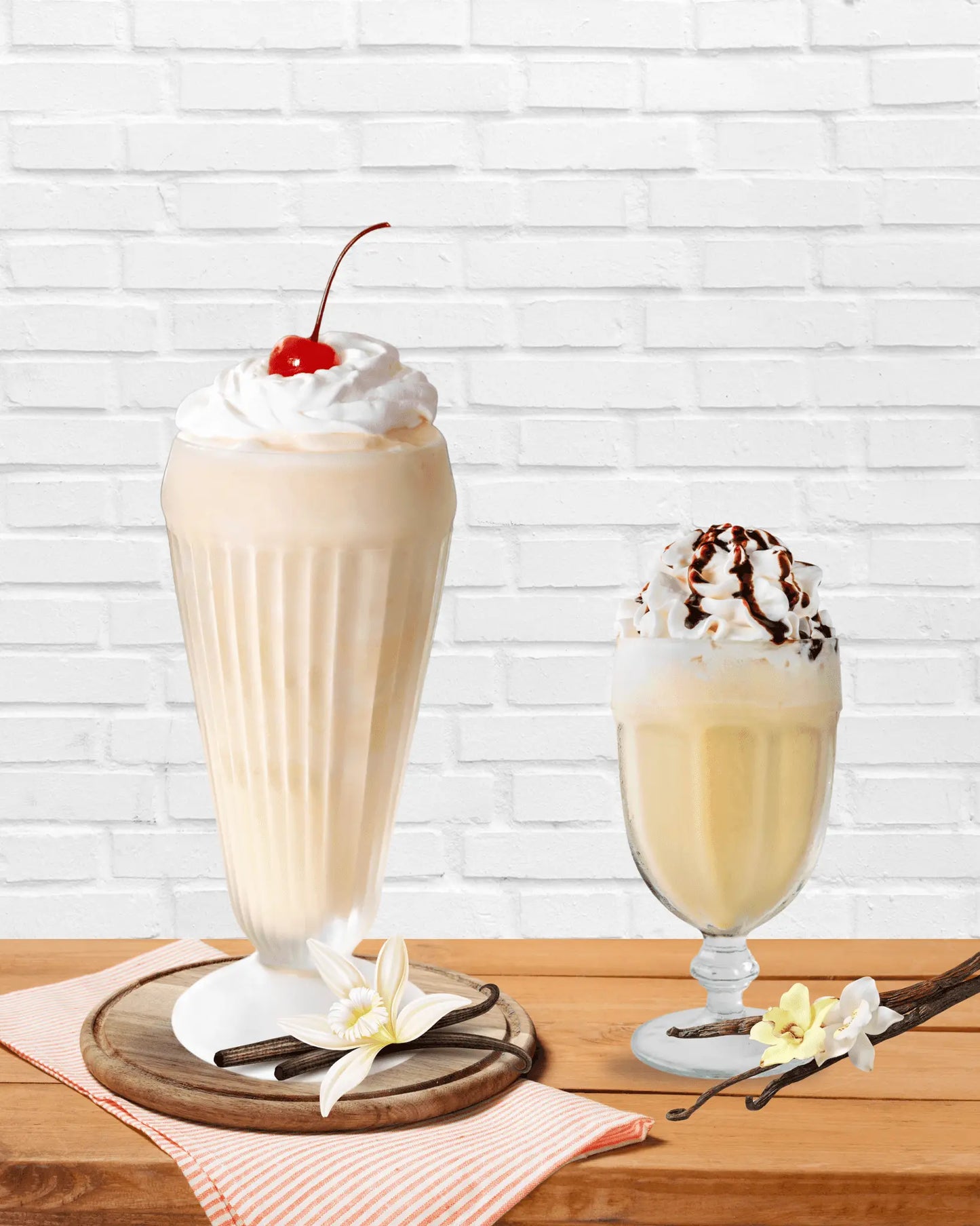 Two vanilla lattes topped with whipped cream and cherry and chocolate drizzle made using the best vanilla powder for lattes