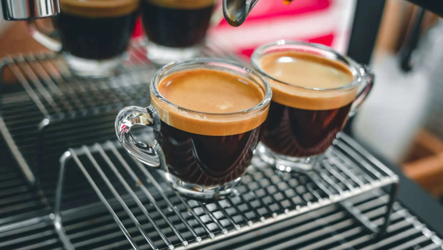Caffeeegy.Co espresso in two glass demitasse cups with rich crema on a machine, locally roasted coffee
