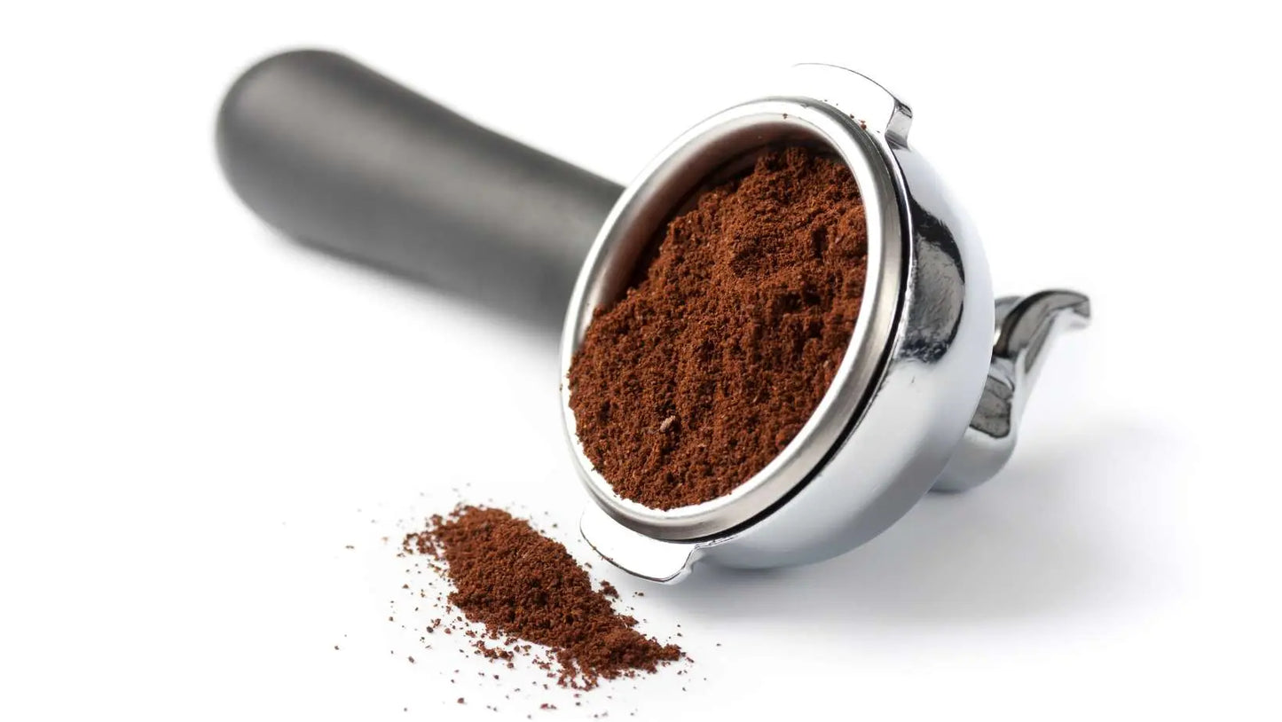 Espresso portafilter filled with fresh ground espresso and spilled grounds showcasing locally roasted coffee