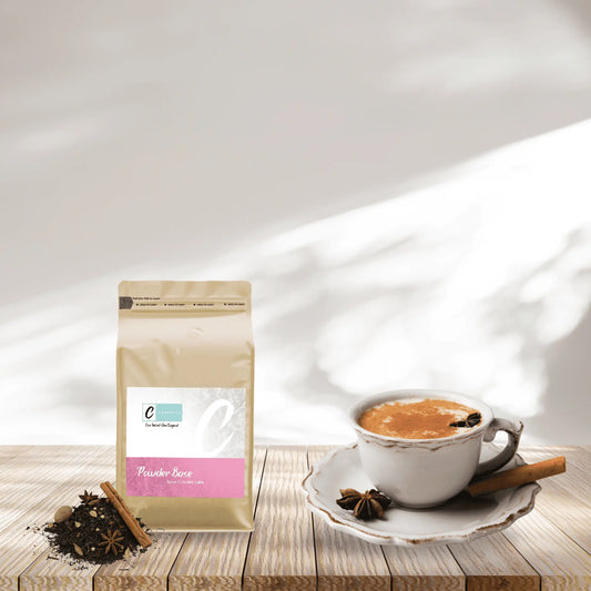 Caffeeegy Co spice chai latte powder package next to a cup of prepared chai latte with spices