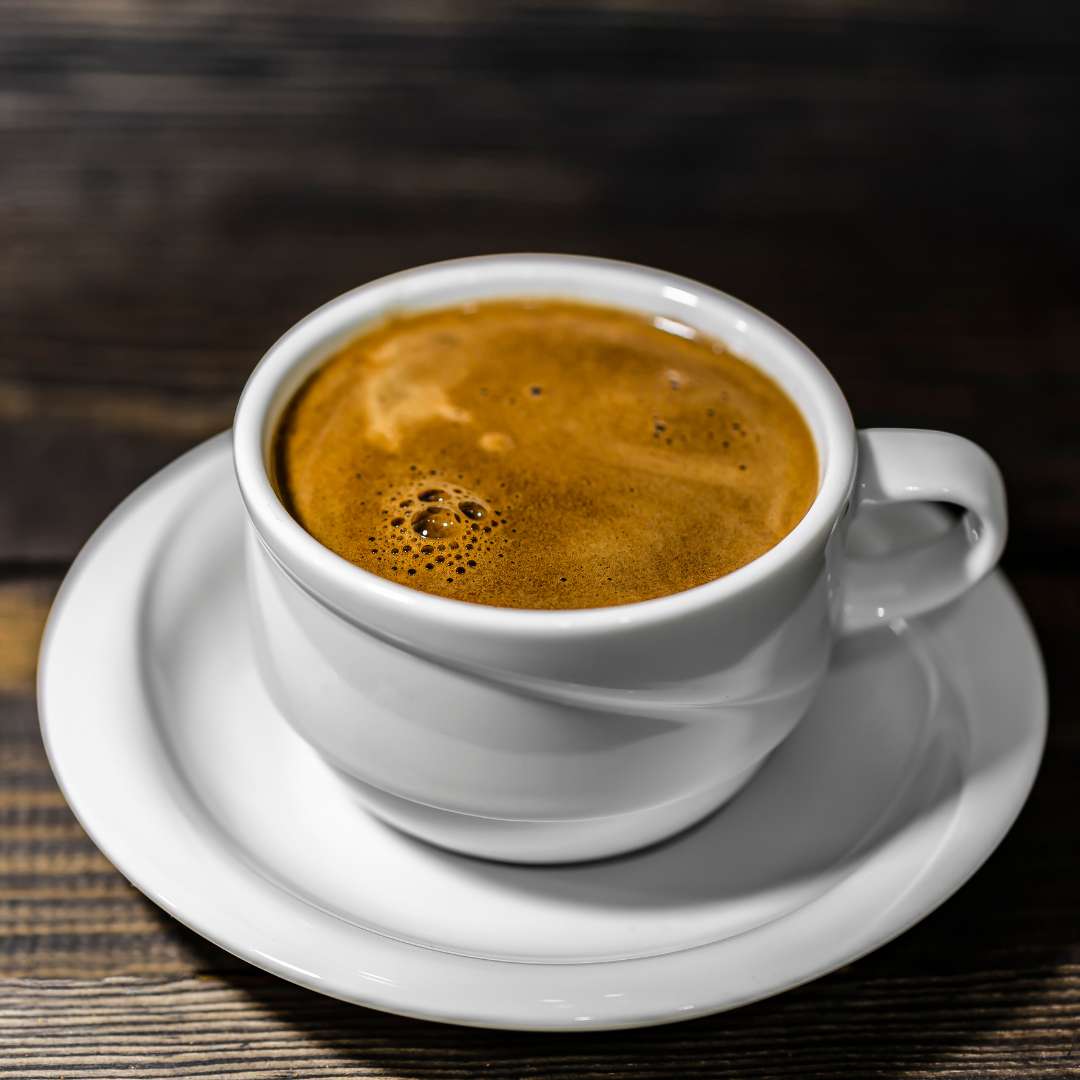 White cup of premium Turkish coffee online from Caffeeegy.Co with rich foam on wooden surface