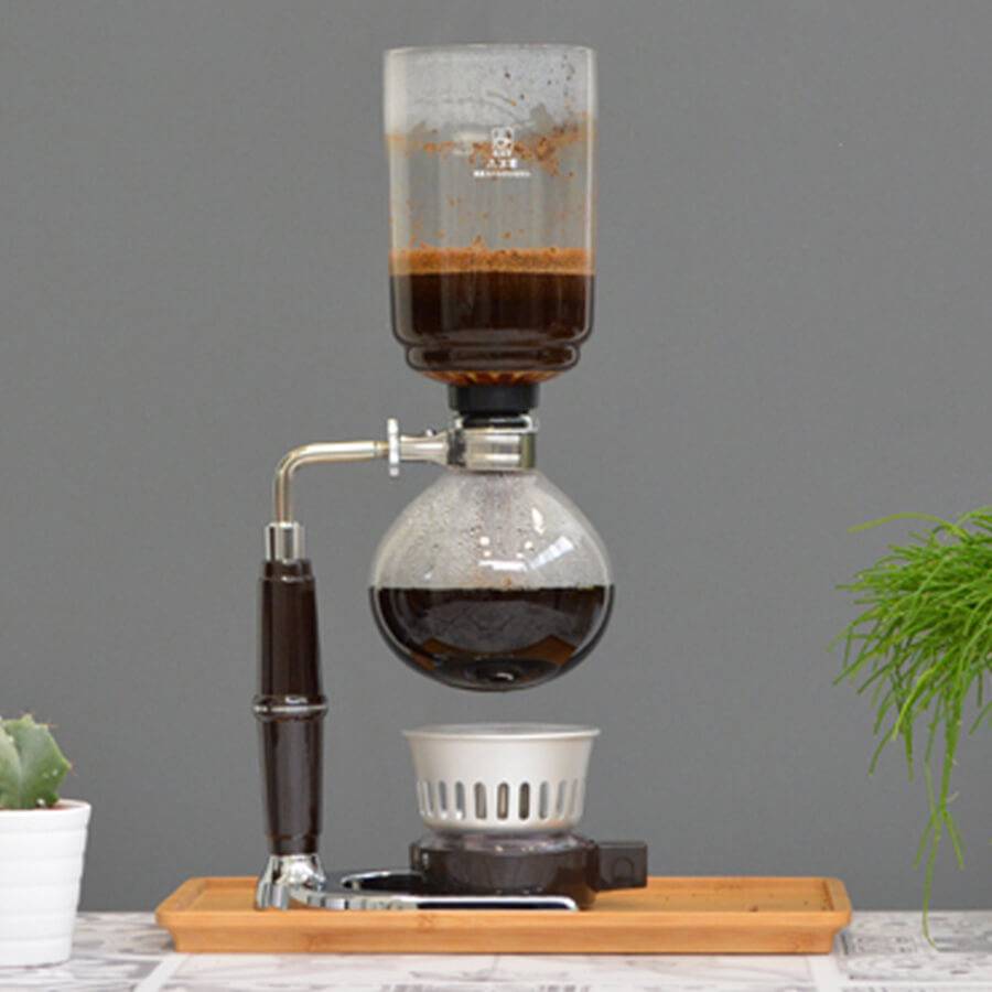 Espresso brewing with premium specialty coffee beans Egypt in a glass siphon coffee maker on wooden tray
