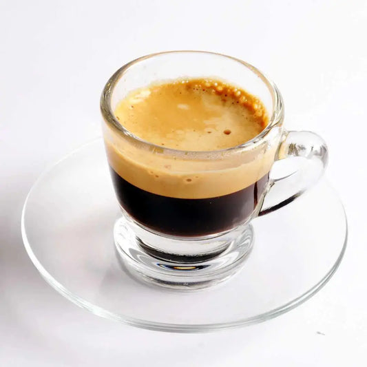 Clear glass espresso cup filled with rich premium espresso coffee blend on a saucer