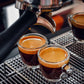 Freshly brewed premium espresso coffee blend served in clear glass cups on a coffee machine