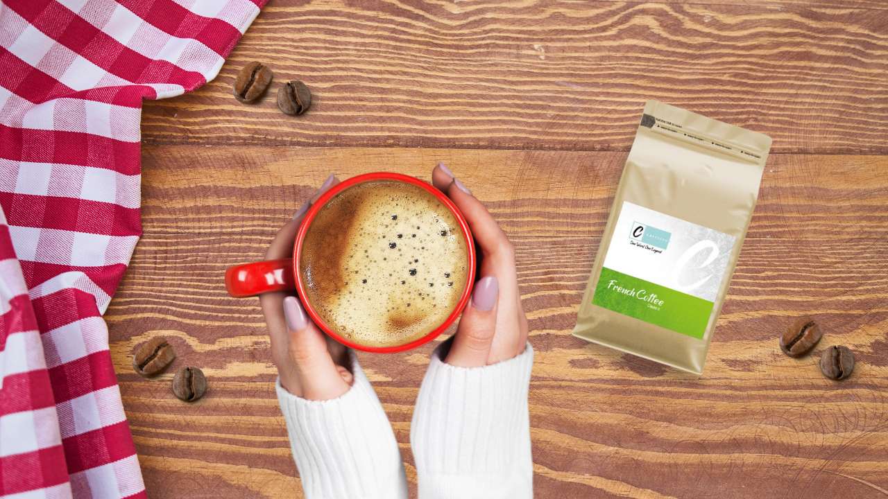 Freshly brewed coffee in a red mug next to French classic coffee beans package on a wooden table