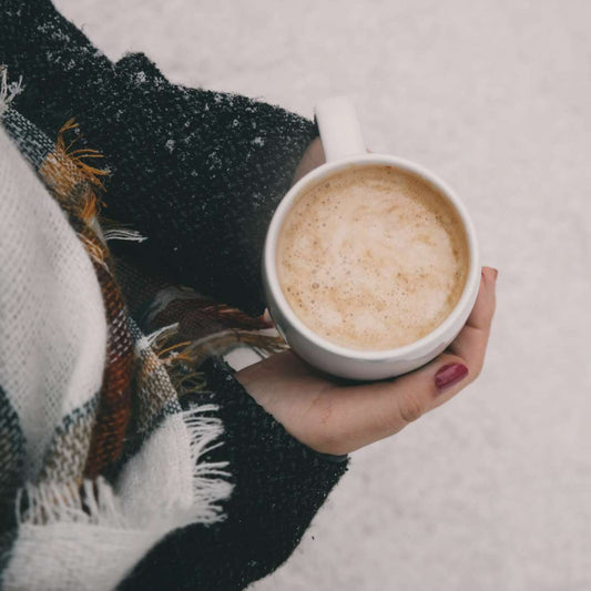 Cup of freshly roasted French coffee held by a person in a cozy sweater